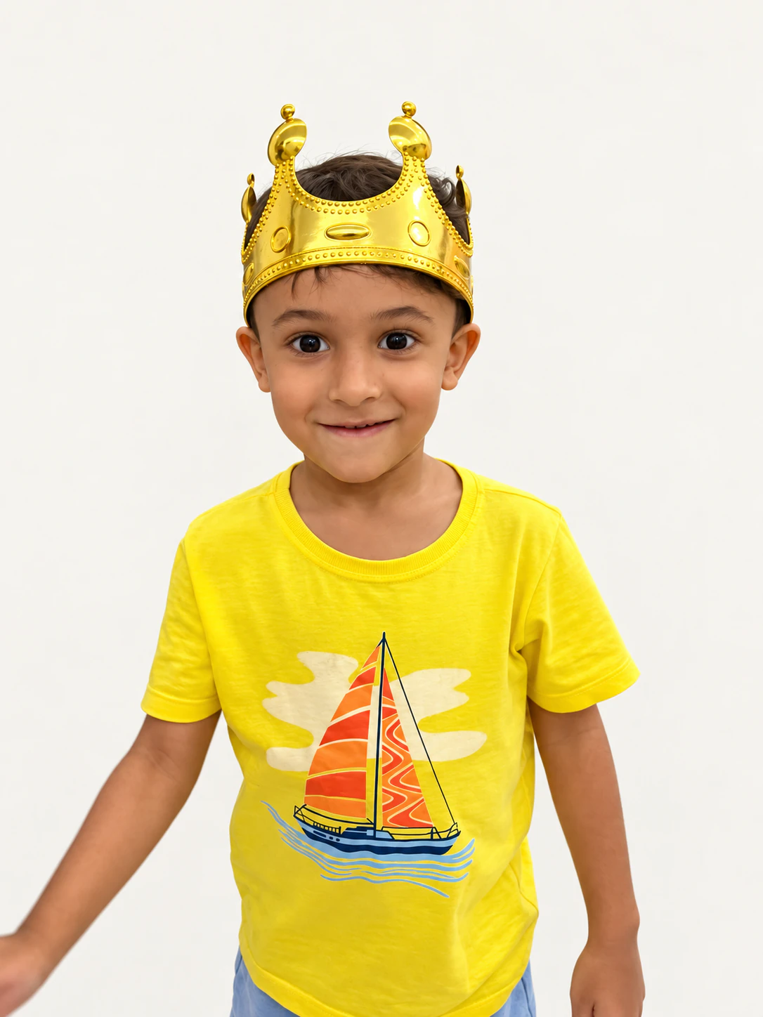 Menino com coroa dourada e camiseta amarela sobre fundo claro